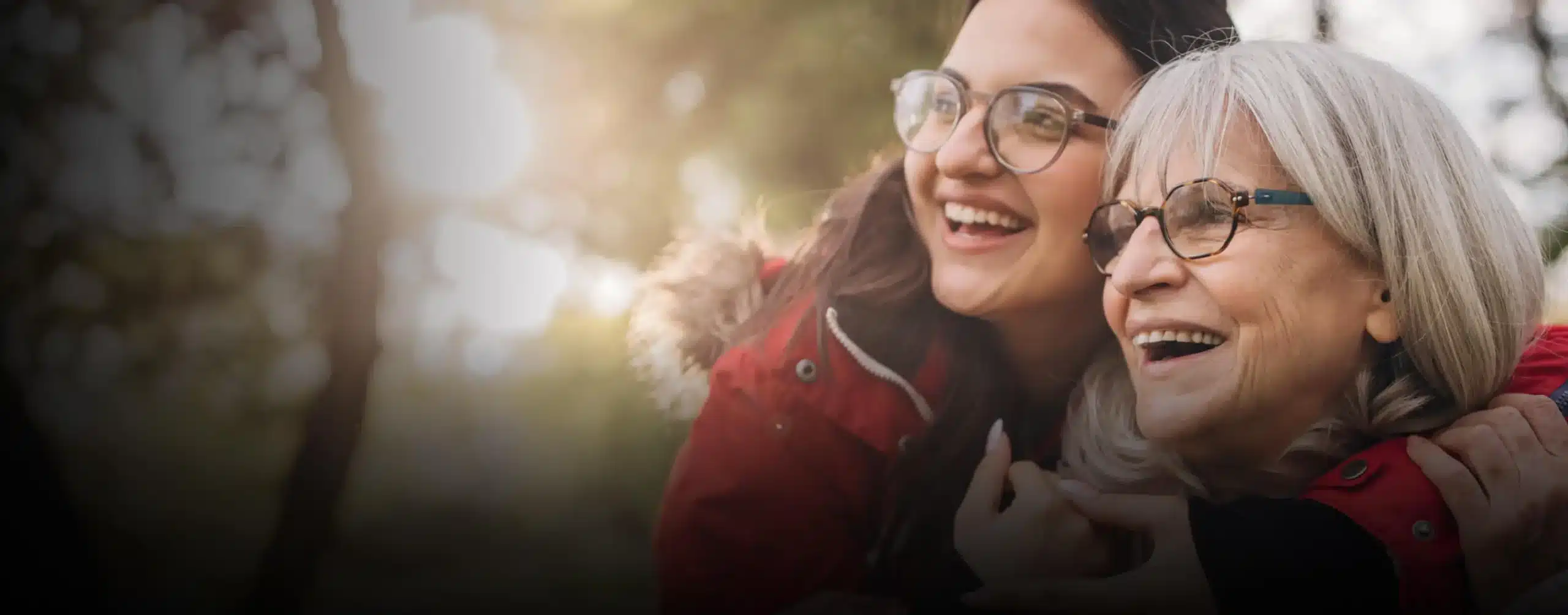 A mother and daughter laugh in nature.