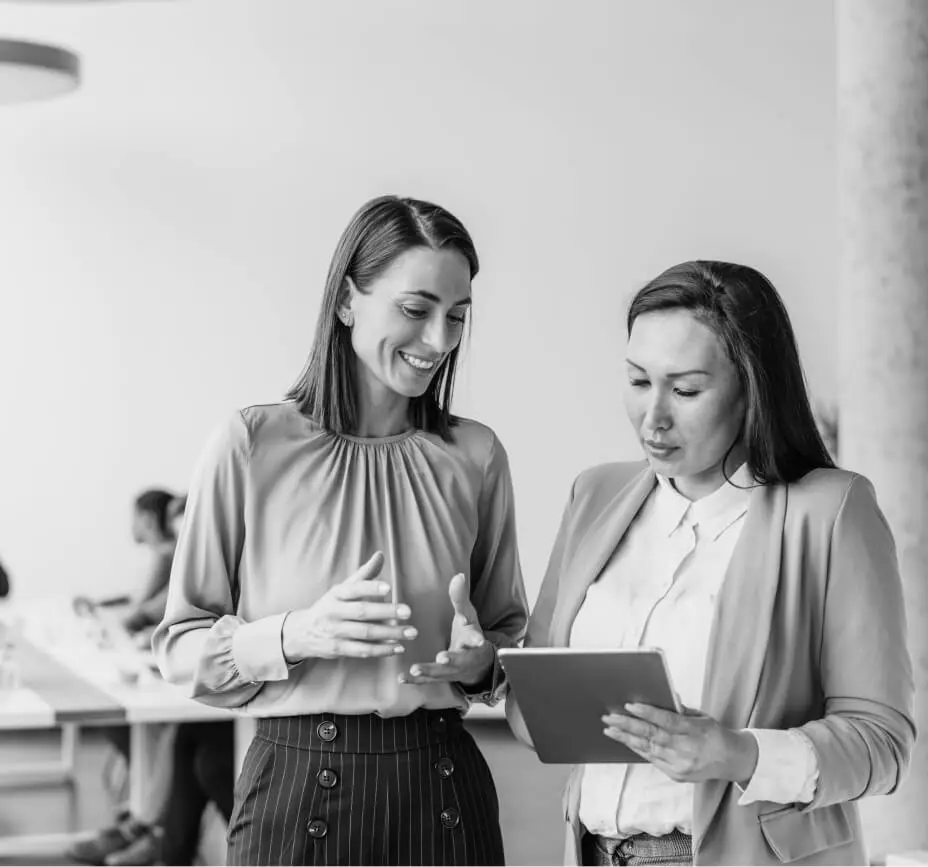 Two colleagues look at a table while in discussion.