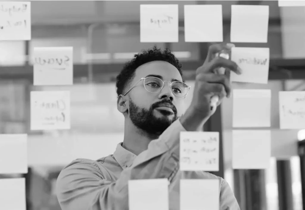 A man adds a sticky note to a sticky note wall.